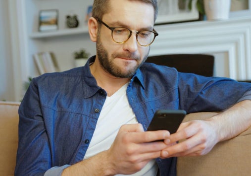 Hombre mirando su teléfono móvil en una sala